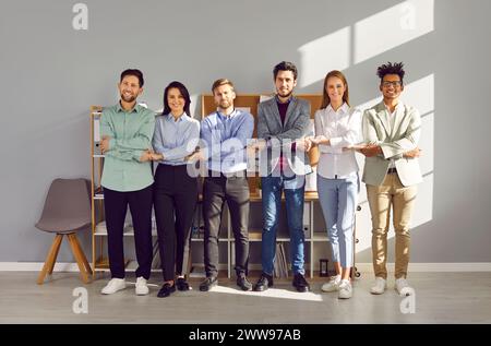 Groupe de personnes souriantes debout dans la rangée se tenant la main dans le bureau Banque D'Images