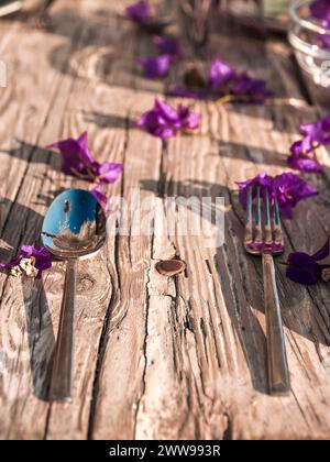 une mise en place romantique et moderne d'un restaurant avec des pétales de bounganville frais qui encadrent une ancienne table en bois Banque D'Images