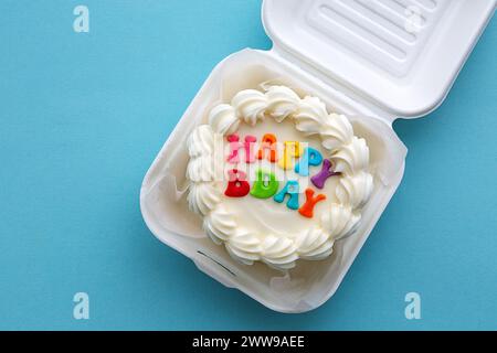 Mini gâteau d'anniversaire avec message coloré joyeux anniversaire dans une boîte à lunch en carton Banque D'Images