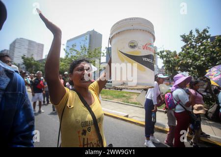 Lima, Pérou. 22 mars 2024. Une femme tient un seau dans lequel elle recueille de l’eau dans son quartier alors qu’elle participe à une manifestation contre la privatisation de l’approvisionnement en eau potable dans la capitale à l’occasion de la Journée mondiale de l’eau. Crédit : Gian Masko/dpa/Alamy Live News Banque D'Images