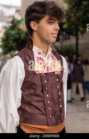 Vibrance valencienne dans les Fallas de Gandia, la tenue traditionnelle d’un homme raconte une histoire de fête. Son costume, orné de broderies élaborées Banque D'Images