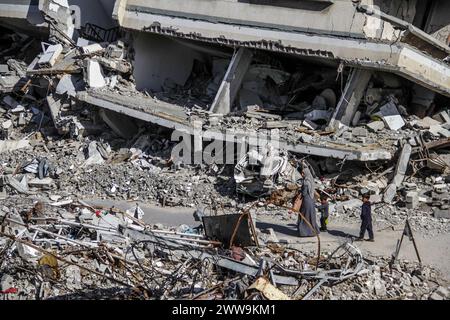 Gaza, Territoires palestiniens. 22 mars 2024. Une femme et deux enfants passent devant les ruines de bâtiments détruits par les bombardements israéliens dans le camp de réfugiés de Jabalia. Crédit : Mahmoud Issa/dpa/Alamy Live News Banque D'Images