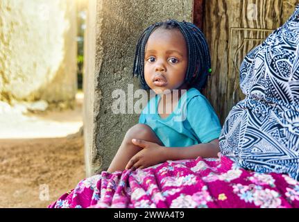 vie de village africain, petite fille avec des tresses situé sur la véranda en fin d'après-midi, Banque D'Images