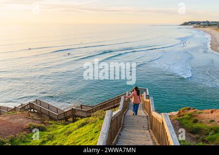 Femme descend gracieusement les escaliers de South Port Beach captivé par la vue spectaculaire sur la mer au coucher du soleil, Port Noarlunga, Australie du Sud Banque D'Images