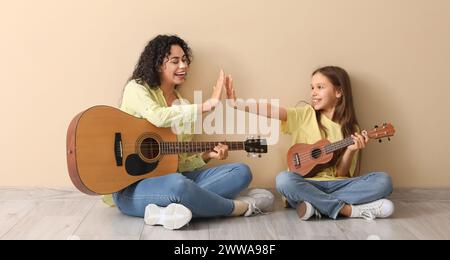 Jeune femme et sa fille jouant de la guitare à la maison Banque D'Images