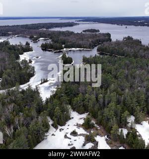 Petites îles boisées dans la rivière des Outaouais à la fin de l'hiver entourées de glace et d'eau libre Banque D'Images