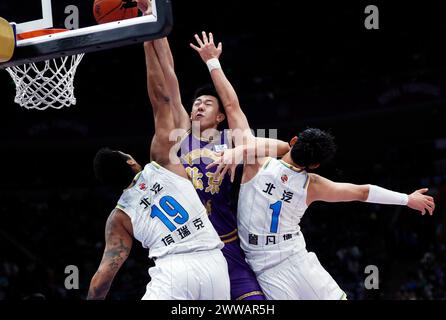 Pékin, Chine. 22 mars 2024. Wang Shaojie (C) de Beijing Royal Fighters va pour un lay-up contre Zeng Fanbo (R) et Taruike Jianiyou de Beijing Ducks lors du match de la 46e ronde de la ligue de l'Association chinoise de basket-ball (CBA) 2023-2024 à Beijing, Chine, le 22 mars 2024. Crédit : Luo Yuan/Xinhua/Alamy Live News Banque D'Images