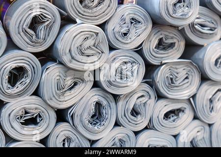 Rouleaux de plastique gris empilés de manière désordonnée, créant un bruit de papier rouleau Banque D'Images