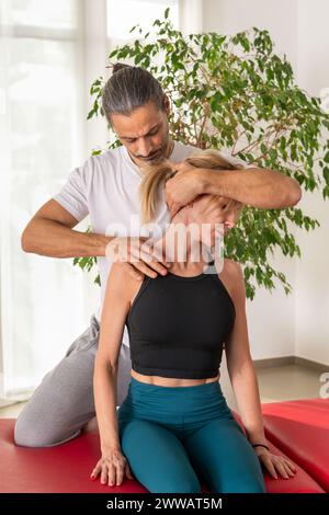 Physiothérapeute faisant confiance cervicale sur l'épaule d'une patiente en salle de massage Banque D'Images