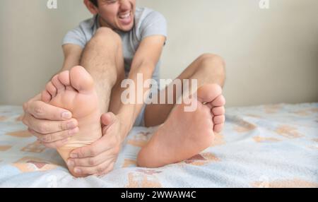 Un homme tenant la voûte plantaire, avec des gestes de douleur souffrante dans certaines parties des pieds. Banque D'Images