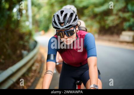 jeune femme asiatique cycliste femme chevauchant le vélo à l'extérieur sur la route rurale Banque D'Images