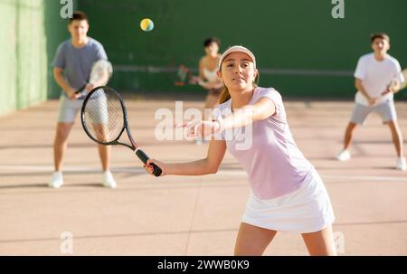 Femme servant le ballon pendant le jeu frontenis à l'extérieur Banque D'Images