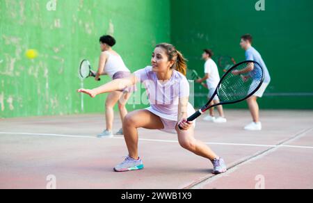 Femme servant le ballon pendant le jeu frontenis à l'extérieur Banque D'Images