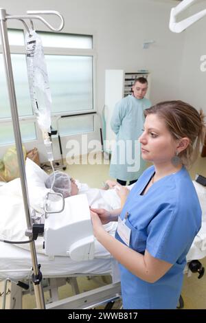 Sage-femme ajustant le débit de la perfusion d'ocytocine / Syntocinon qui va induire le travail en accélérant les contractions. Banque D'Images