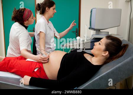 Hôpital. Maternité. étudiante sage-femme de 4e année réalisant une échographie prénatale sous la supervision d'une sage-femme. 24 semaines, 6 mois femme enceinte. Banque D'Images