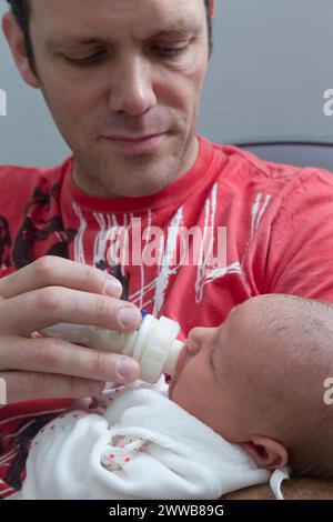 Père donnant le biberon à son enfant à la maternité. Banque D'Images