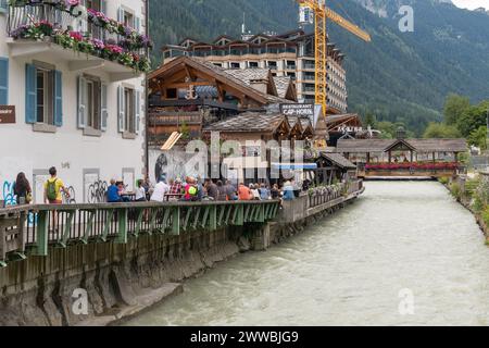 Foule de gens dans un café en plein air avec de la musique live donnant sur la rivière Arve à l'happy hour en été, Chamonix, haute Savoie, France Banque D'Images