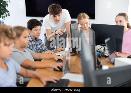 Enseignant homme positif avec le garçon enseigne comment travailler sur ordinateur Banque D'Images