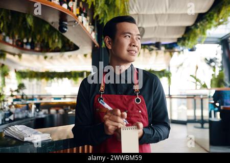 Serveur de restaurant vietnamien souriant écrivant la commande Banque D'Images