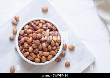 Haricots romains séchés non cuits dans un bol ou une cuillère sur la table, tas de légumineuses concept de haricots rouges Banque D'Images