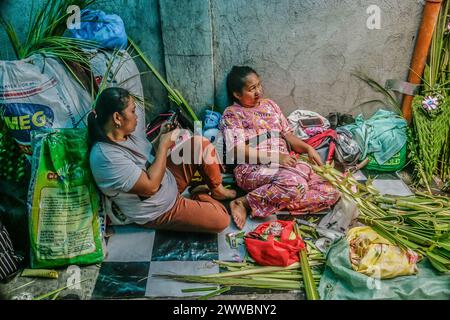 Antipolo City, Philippines. 23 mars 2024. Les femmes fabriquent des frondes de palmier dans la rue en préparation du dimanche des Rameaux à Antipolo City. Les frondes de palmier ont été historiquement liées à la victoire et au triomphe dans de nombreuses cultures. Le dimanche des Rameaux, qui, selon les fidèles catholiques, marque le début de la semaine dite semaine Sainte. (Photo de Ryan Eduard Benaid/SOPA images/Sipa USA) crédit : Sipa USA/Alamy Live News Banque D'Images