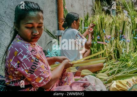 Antipolo City, Philippines. 23 mars 2024. Les femmes fabriquent des frondes de palmier dans la rue en préparation du dimanche des Rameaux à Antipolo City. Les frondes de palmier ont été historiquement liées à la victoire et au triomphe dans de nombreuses cultures. Le dimanche des Rameaux, qui, selon les fidèles catholiques, marque le début de la semaine dite semaine Sainte. (Photo de Ryan Eduard Benaid/SOPA images/Sipa USA) crédit : Sipa USA/Alamy Live News Banque D'Images