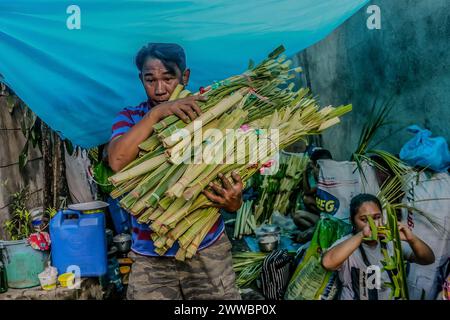 Antipolo City, Philippines. 23 mars 2024. Un homme porte des frondes de palmier dans la rue en préparation du dimanche des Rameaux à Antipolo City. Les frondes de palmier ont été historiquement liées à la victoire et au triomphe dans de nombreuses cultures. Le dimanche des Rameaux, qui, selon les fidèles catholiques, marque le début de la semaine dite semaine Sainte. (Photo de Ryan Eduard Benaid/SOPA images/Sipa USA) crédit : Sipa USA/Alamy Live News Banque D'Images