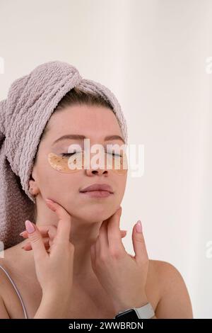 Application de patchs oculaires dans la routine de soin de la peau. Fille avec naturel sans maquillage avec silicone sous les patchs oculaires Banque D'Images