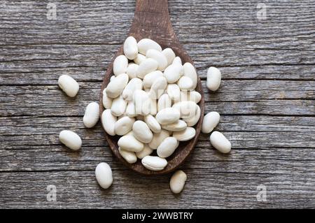 Haricots blancs séchés non cuits dans un bol ou une cuillère sur la table. Tas de légumineuses haricots de fond ( Phaseolus vulgaris ) Banque D'Images