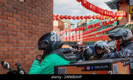 Les clients qui livrent de la nourriture font une pause à Chinatown, Londres. Banque D'Images