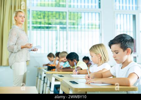 Préadolescents scolaires travaillant diligemment en classe avec un enseignant Banque D'Images