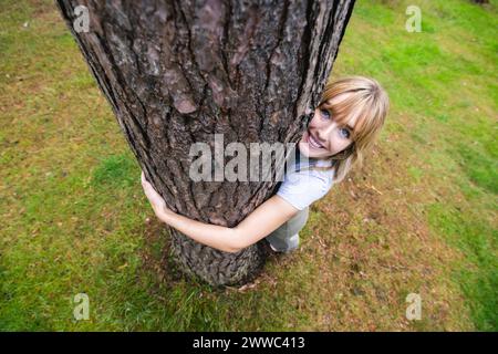 Souriante belle femme embrassant l'arbre Banque D'Images