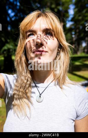 Heureuse jeune femme avec ombre sur le visage le jour ensoleillé Banque D'Images