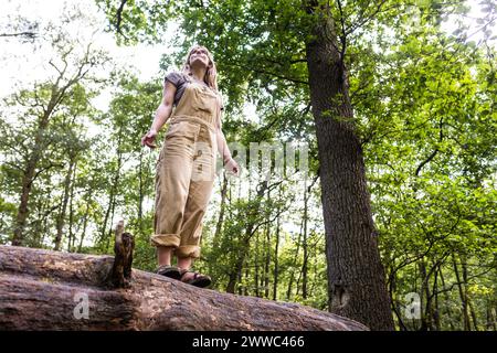 Jeune femme debout sur le tronc d'arbre dans la forêt Banque D'Images