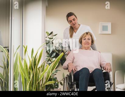 Soignant à domicile avec femme âgée assise en fauteuil roulant Banque D'Images
