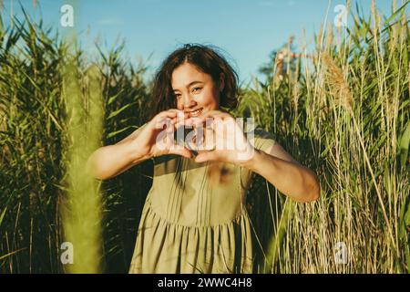 Femme heureuse faisant des gestes en forme de coeur dans le champ Banque D'Images