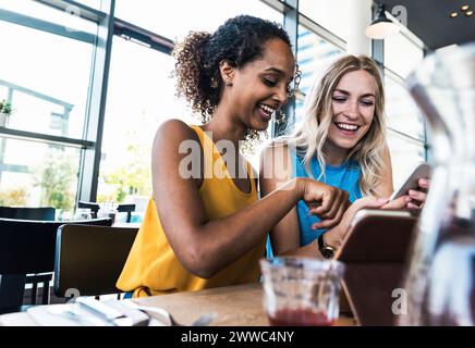Heureux jeunes amis s'amusant assis dans le restaurant Banque D'Images