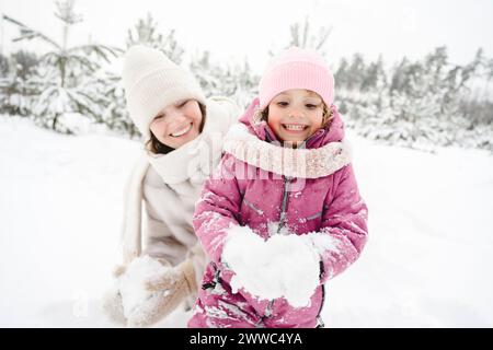 Heureuse mère et fille jouant avec la neige au parc d'hiver Banque D'Images