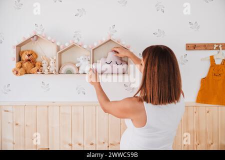 Femme enceinte décorant la chambre avec des jouets à la maison Banque D'Images