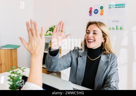 Heureuse femme d'affaires donnant high-five à un collègue au bureau Banque D'Images