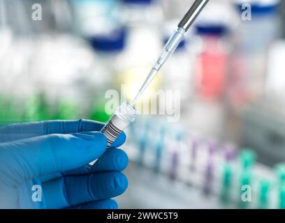 Mains d'un scientifique pipettant un échantillon d'ADN dans un flacon au laboratoire Banque D'Images