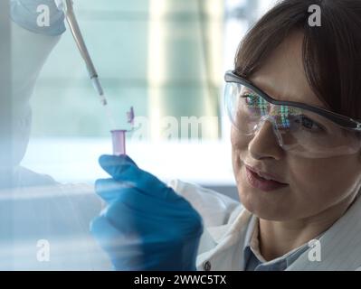 Scientifique pipettant un échantillon d'ADN dans un tube eppendorf en laboratoire Banque D'Images