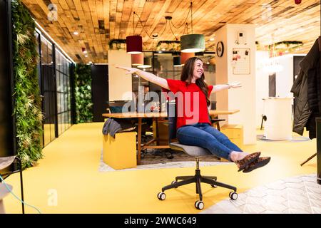 Femme d'affaires insouciante s'amusant sur la chaise dans le bureau Banque D'Images