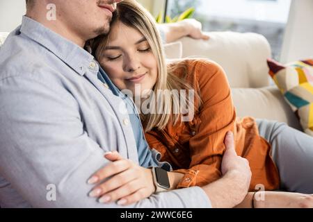 Femme souriante embrassant l'homme sur le canapé à la maison Banque D'Images