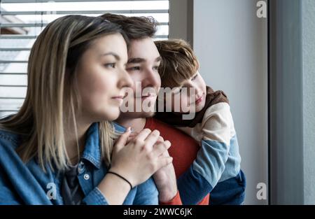 Père et mère avec fils regardant par la fenêtre à la maison Banque D'Images