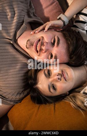 Jeune couple souriant allongé sur des coussins Banque D'Images