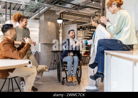 Homme d'affaires en fauteuil roulant donnant du café à des collègues au café de bureau Banque D'Images
