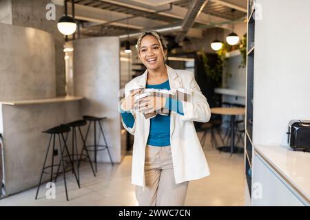 Jeune femme d'affaires portant le café dans des tasses jetables au café de bureau Banque D'Images