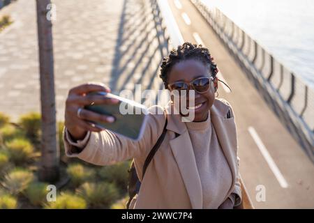 Femme souriante prenant le selfie par téléphone portable Banque D'Images