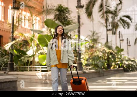 Femme souriante marchant avec une valise à la gare Banque D'Images